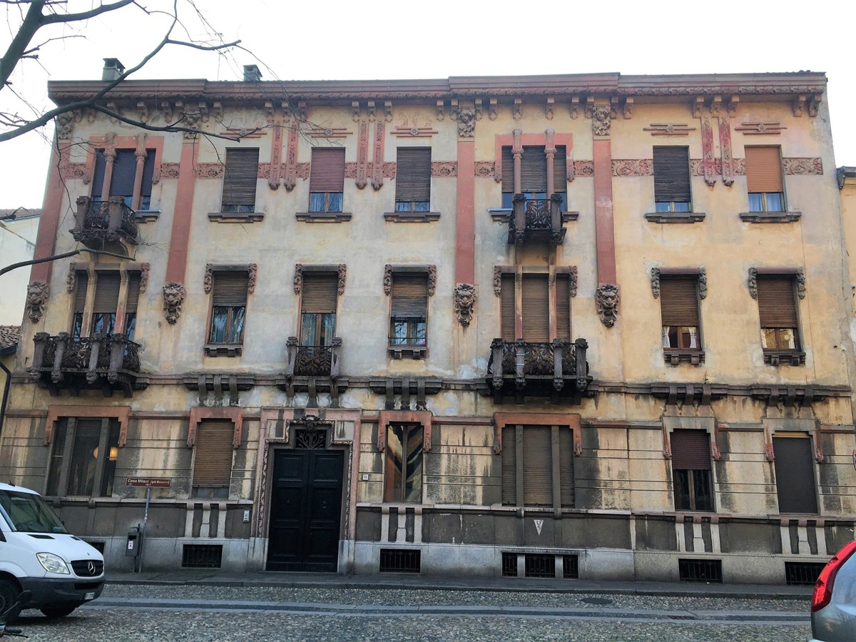 Facciata di casa Milani in piazza San Pietro in Ciel d'Oro a Pavia, con decorazioni rosse e balconi in ferro battuto