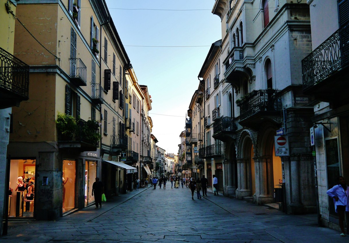 Strada Nuova a Pavia al tramonto, con le vetrine dei negozi e i balconi dei palazzi