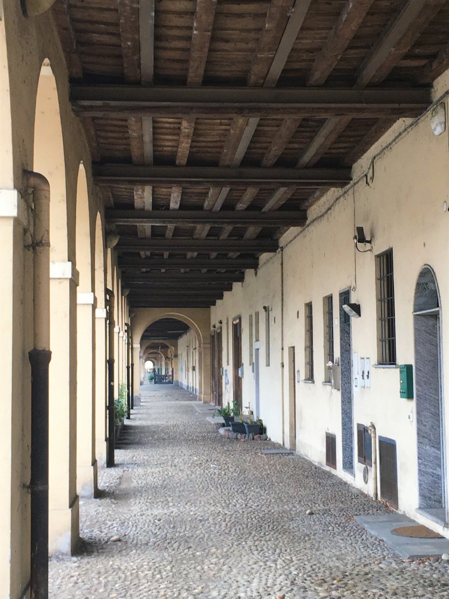Il lungo portico di Borgo Calvenzano a Pavia, con le arcate e il soffitto in legno