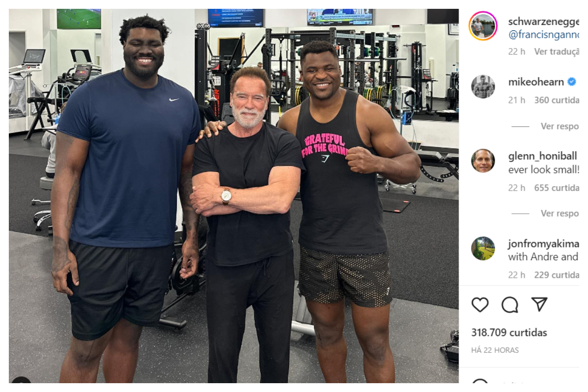 Arnold Schwarzenegger cercado por Francis Ngannou e Mekhi Becton em Los Angeles.