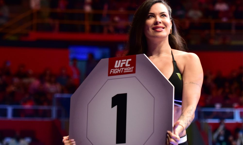 Camila Oliveira segura a placa indicando o round 1 de uma luta do UFC SP