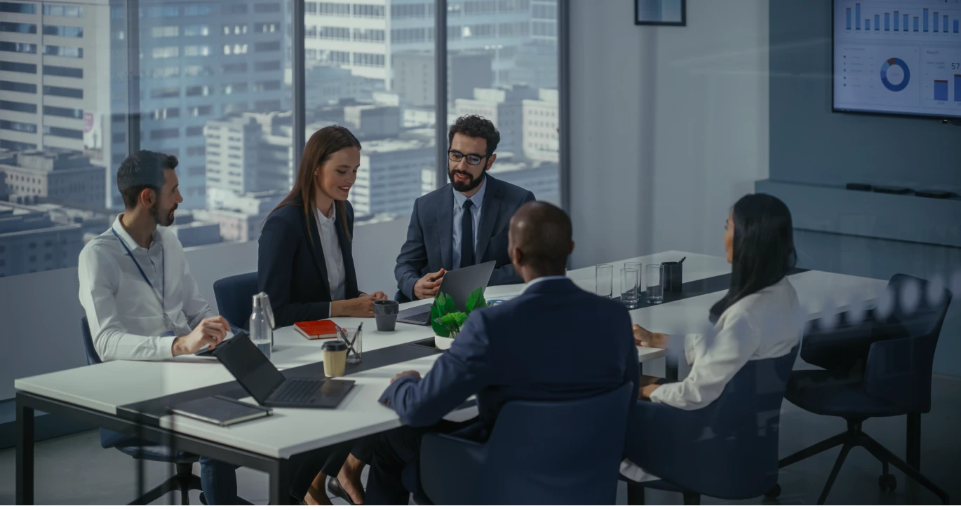 Fünf Personen sitzen im Büro an einem großen Tisch. Geschäftliche Besprechung