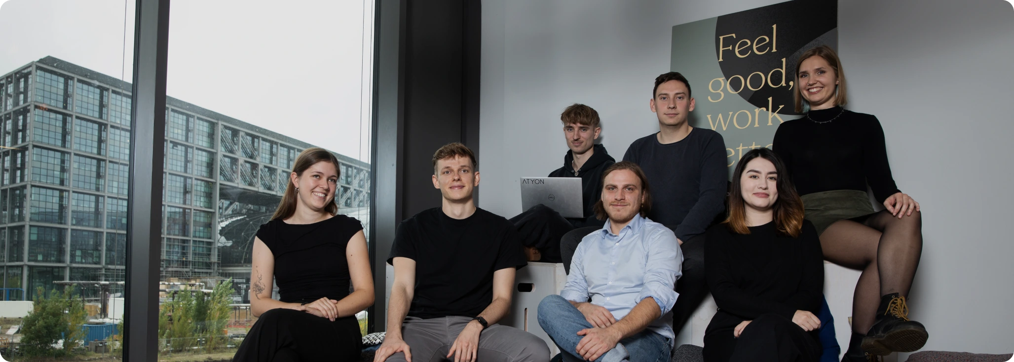 Unser Team Eine Gruppe von sieben jungen Menschen sitzt und lächelt in die Kamera.