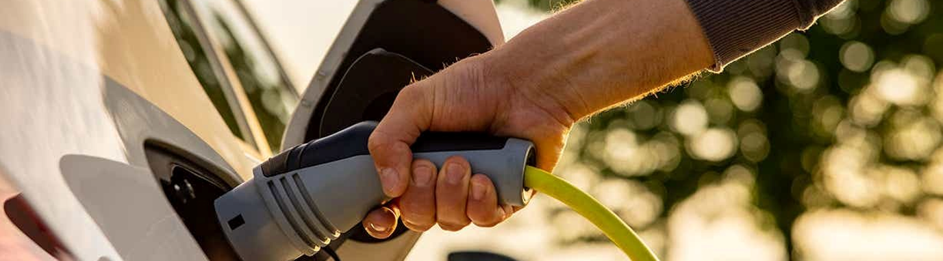 Eine Hand hält einen Ladestecker für Elektrofahrzeuge