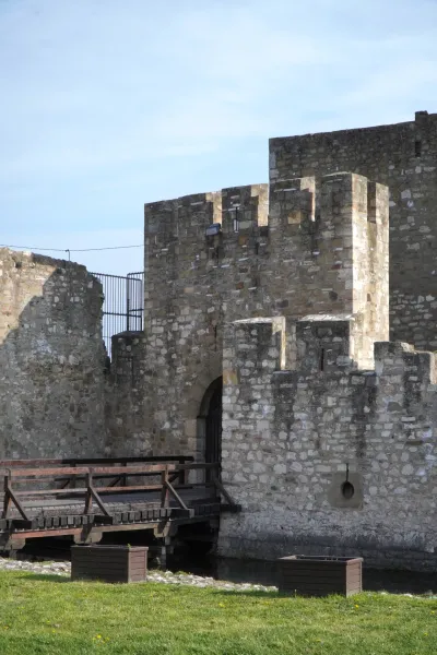 Un puente levadizo de madera conduce a una puerta de piedra de la Fortaleza de Smederevo en Serbia, flanqueada por un foso y céspedes.