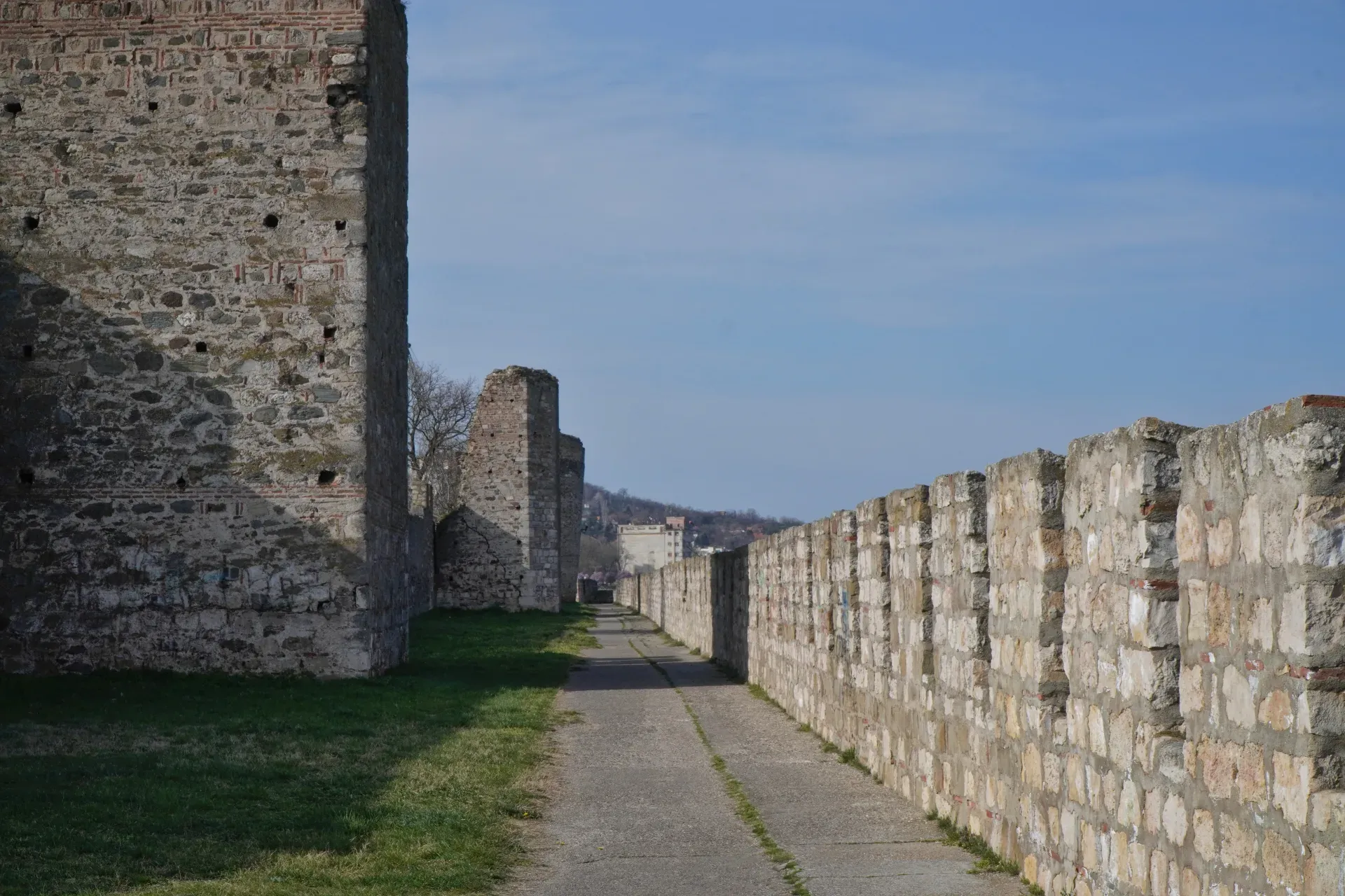 Eine Straße führt durch die Festungsmauern von Smederevo, Serbien, mit steinernen Türmen und einer Stadt im Hintergrund.