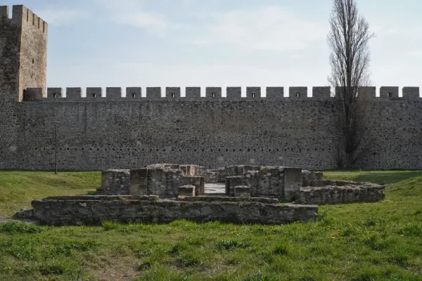 Les vestiges d'un complexe sacré dans la forteresse de Smederevo, Serbie, devant un mur de pierre massif et un grand arbre.
