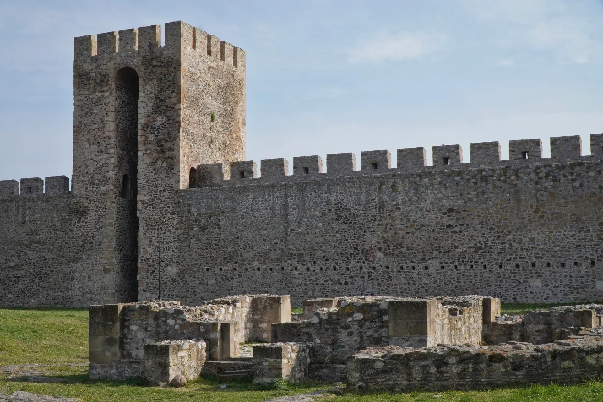 Las ruinas de un edificio religioso son visibles frente a la imponente muralla de piedra y la torre de vigilancia de la Fortaleza de Smederevo en Serbia.