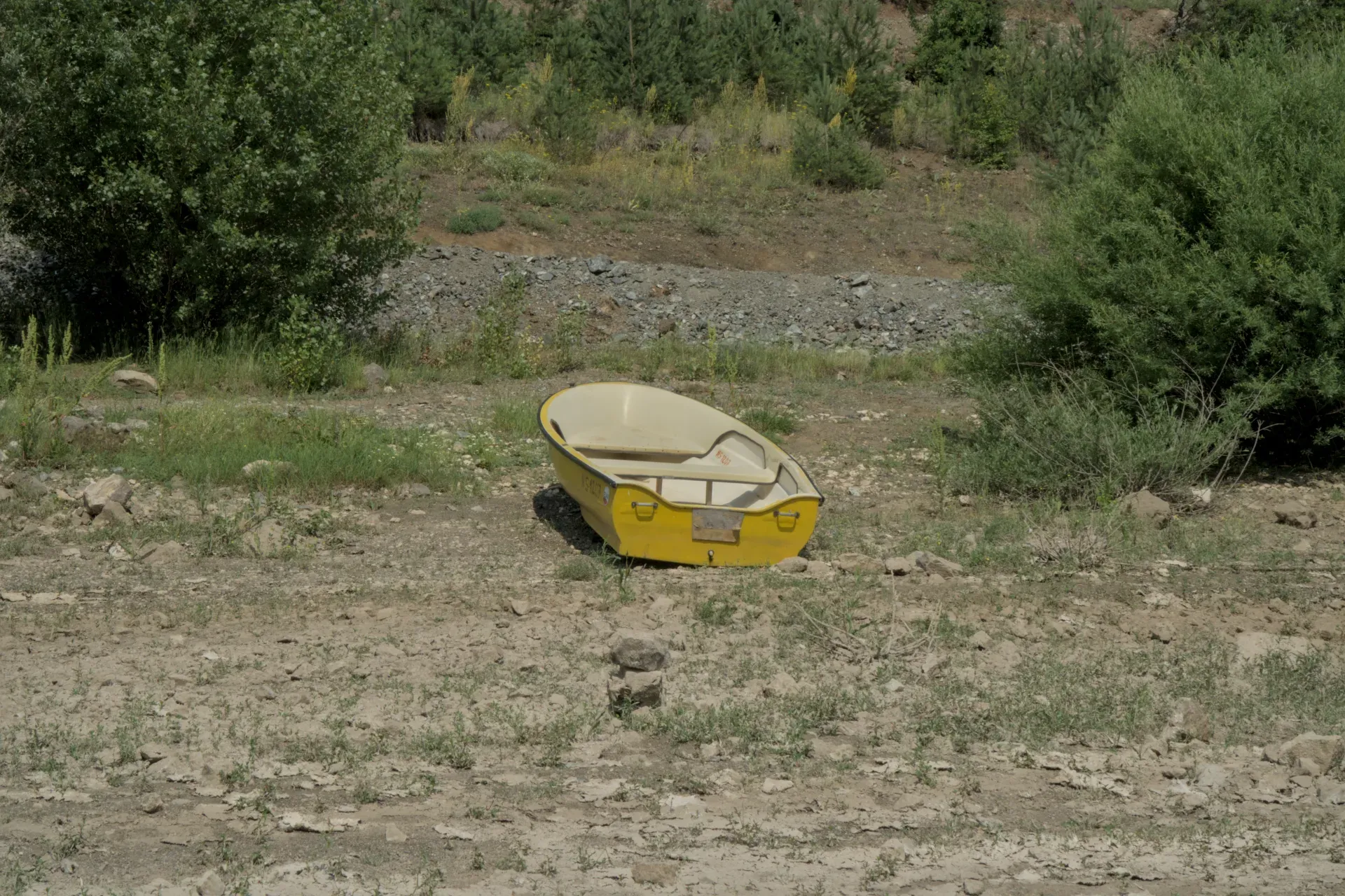 Ein gelbes Boot liegt am steinigen Ufer des Zaovine-Sees, umgeben von grüner Vegetation, im Tara Nationalpark, Serbien.
