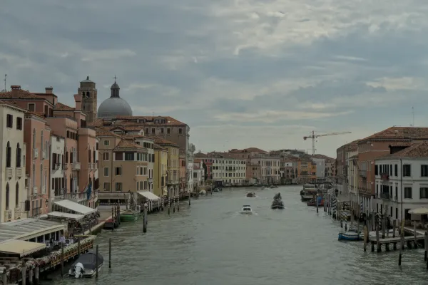 Der Canal Grande in Venedig mit traditionellen, pastellfarbenen Gebäuden und Booten auf dem Wasser, aufgenommen bei bewölktem Himmel.