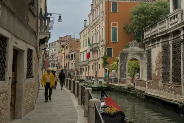 Eine schmale Gasse in Venedig führt zu einem Kanal, gesäumt von historischen Gebäuden und einer Gondel.