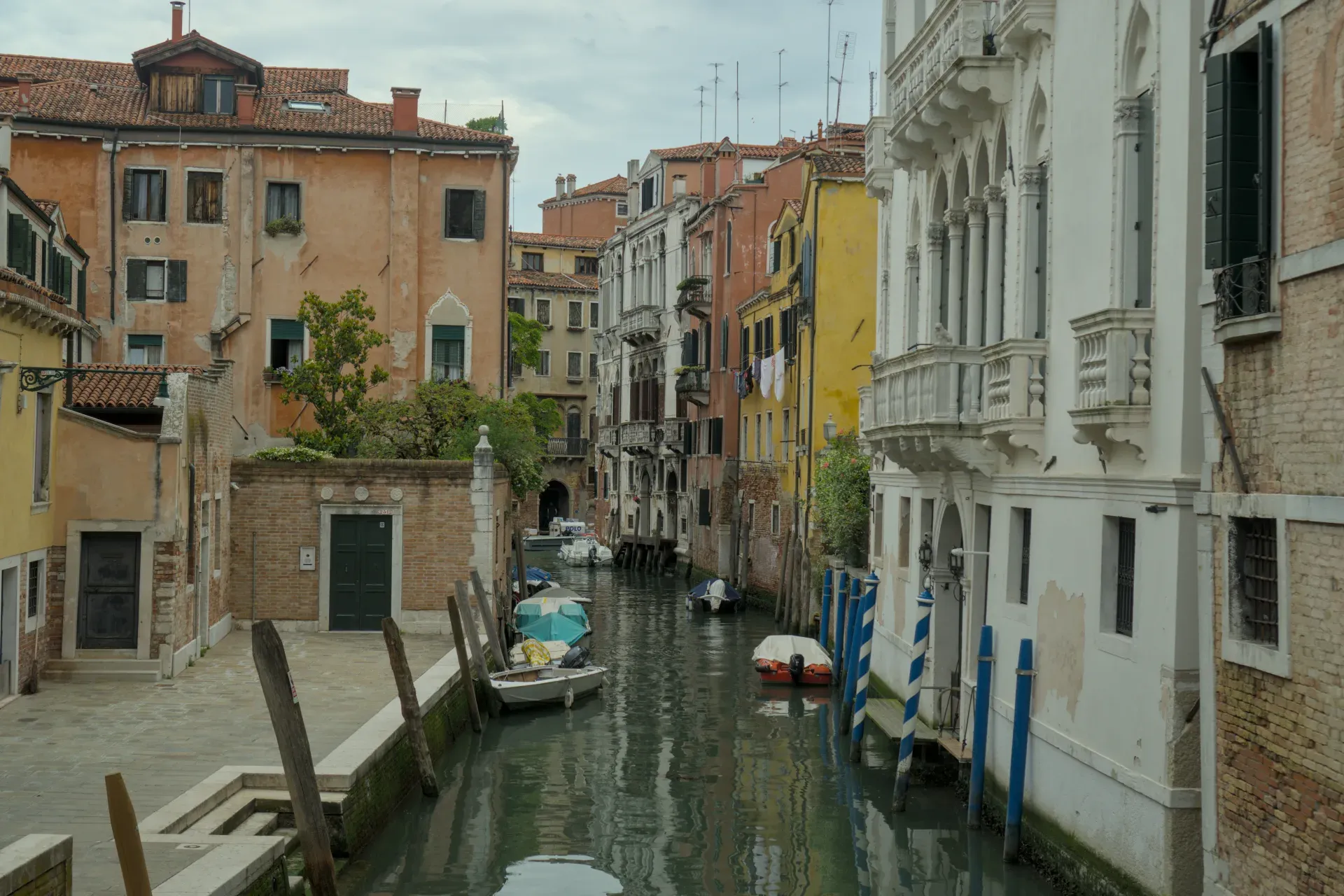 A narrow canal in Venice lined with historic buildings and several boats resting on the water.