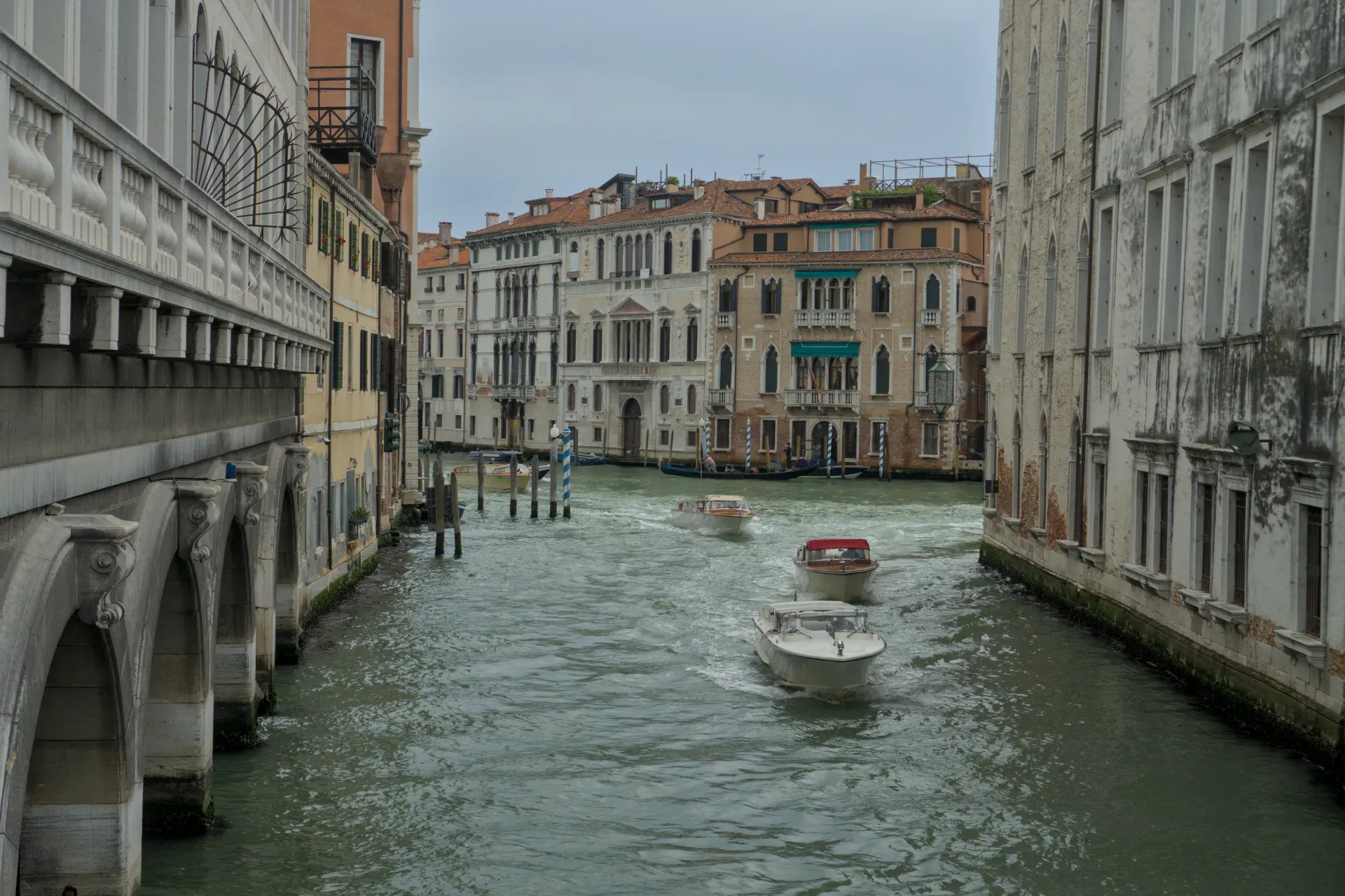 Boote auf dem Canal Grande in Venedig, umgeben von historischen Gebäuden und einer Brücke.