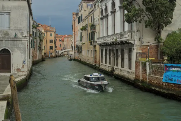 Un bateau sur un canal vénitien entouré de bâtiments historiques et d'eau turquoise.