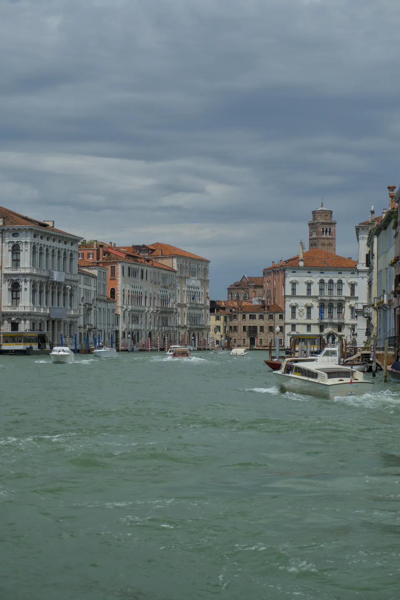 Gran Canal en Venecia con edificios históricos y barcos bajo un cielo dramático.