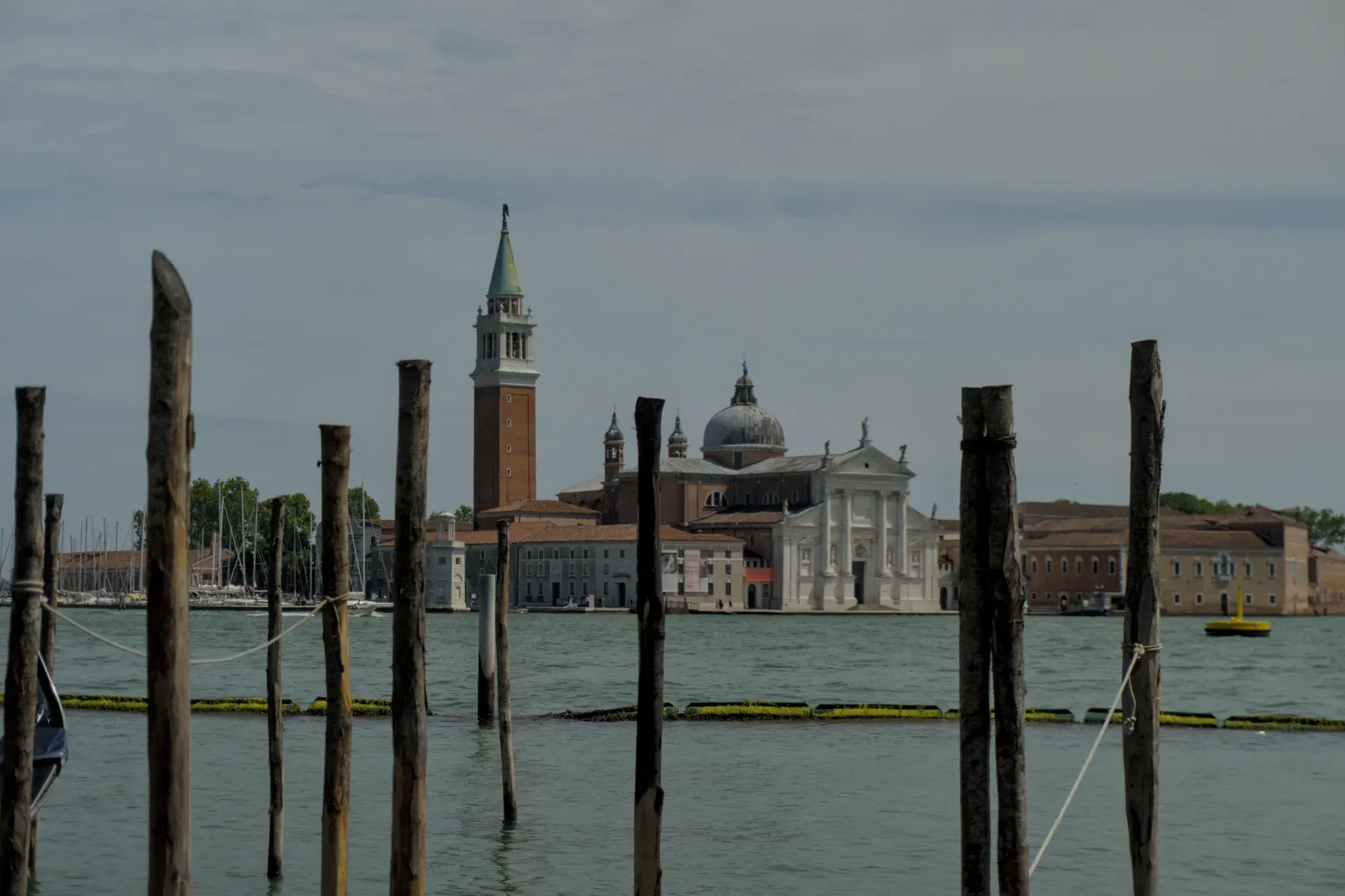 L'église San Giorgio Maggiore à Venise, Italie, avec sa tour distinctive, vue sur l'eau depuis les poteaux en bois au premier plan.
