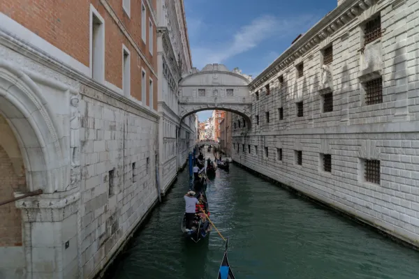 Des gondoles descendent un canal à Venise, Italie, passant sous un pont historique.