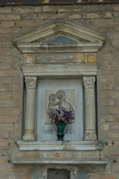 Sculpture religieuse de la Vierge à l'Enfant avec des fleurs dans une niche en pierre, adaptée à la décoration murale.