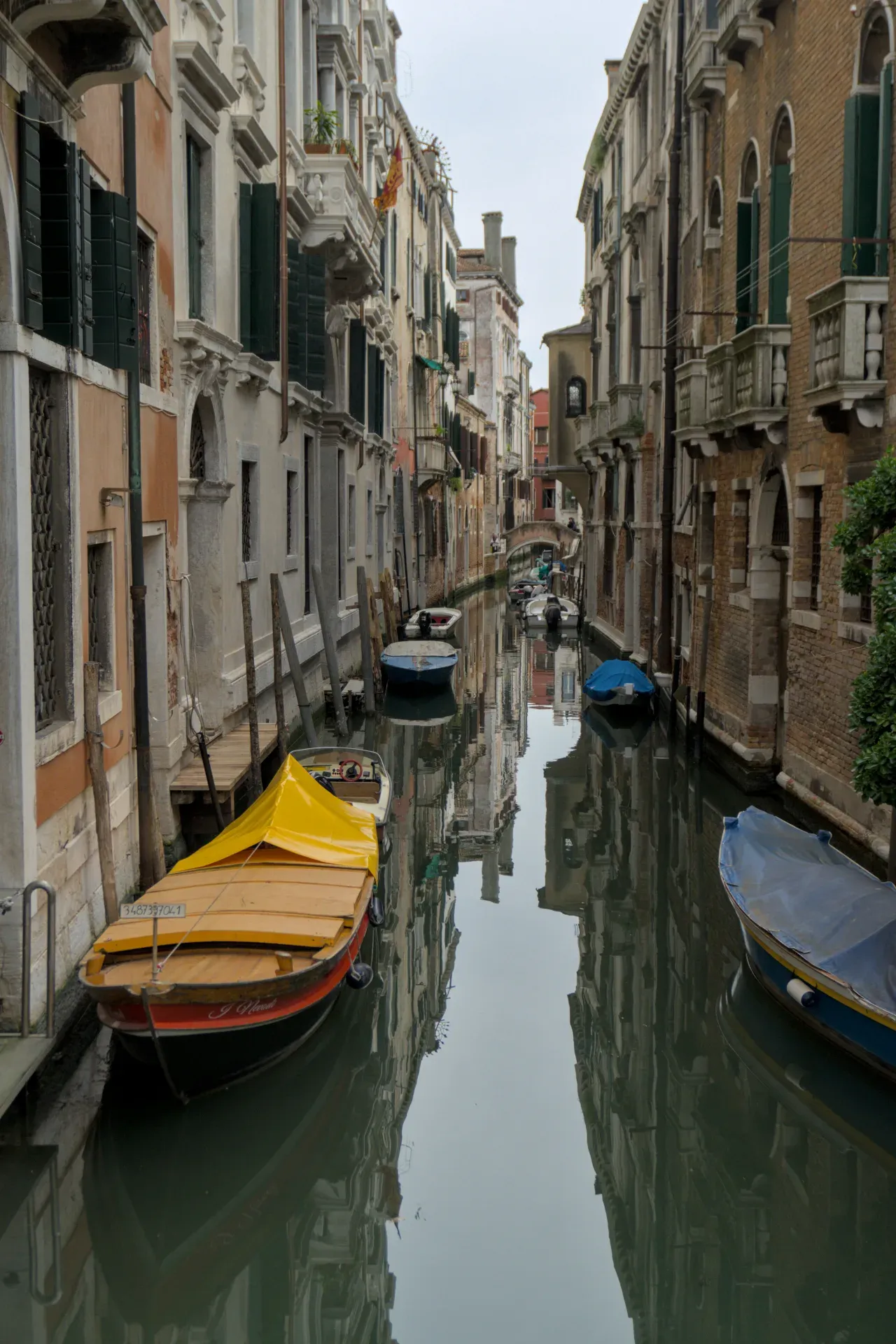 Ein schmaler Kanal in Venedig mit Booten und reflektierenden Gebäuden, perfekt für Wandkunst.