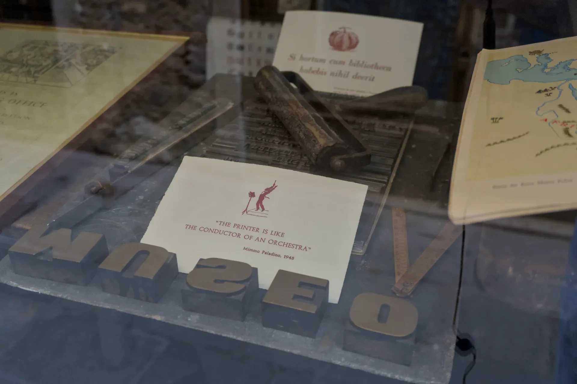 Antike Druckerei-Artefakte in Venedig, darunter Bleilettern und ein Druckwerkzeug, präsentiert hinter Glas.