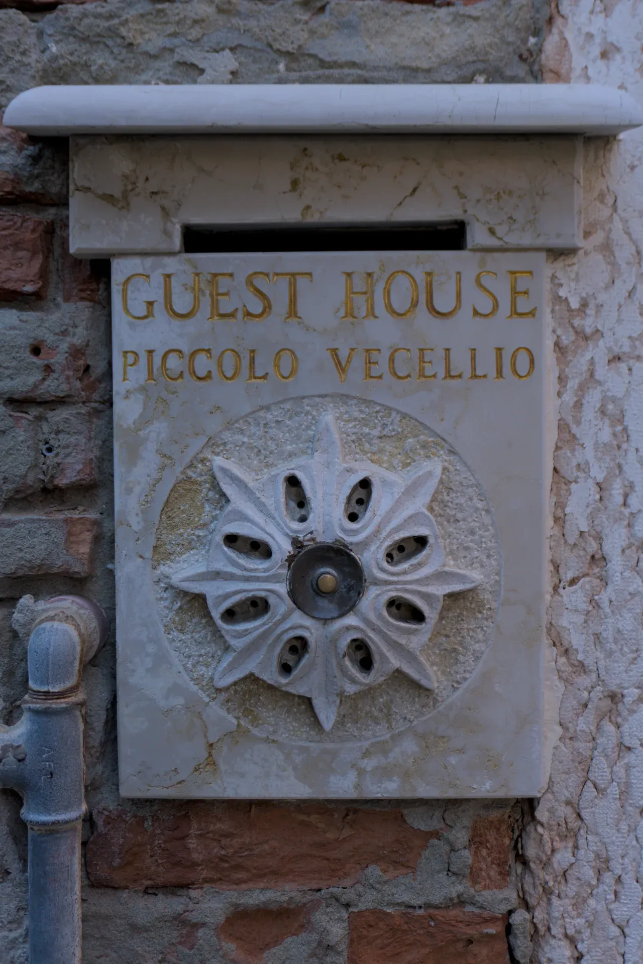 Señal de la Casa de Huéspedes Piccolo Vecellio con letras doradas sobre mármol, Venecia.