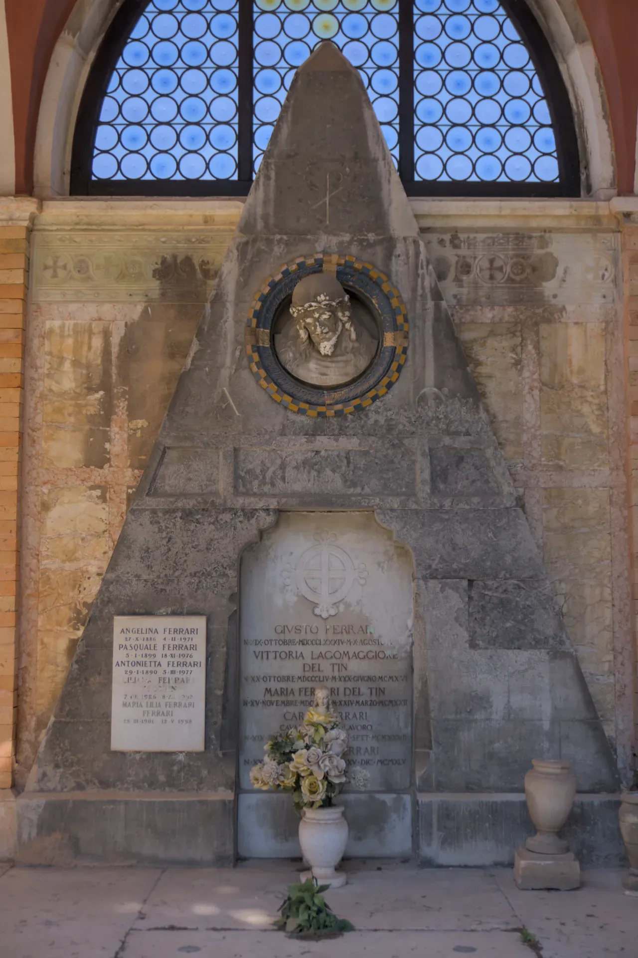 Un portrait éthéré d'une tombe au cimetière de San Michele à Venise, avec un buste et un arrangement floral.