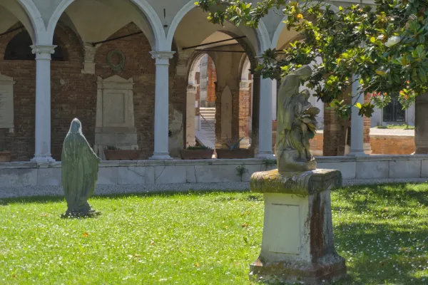 Cimetière San Michele Venise avec sculptures et arcades au soleil.