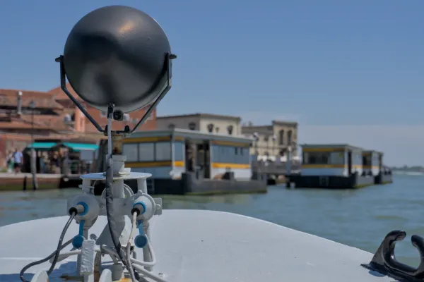 Un bateau-bus s'approche de l'île de Murano, avec des bâtiments et de l'eau en arrière-plan.