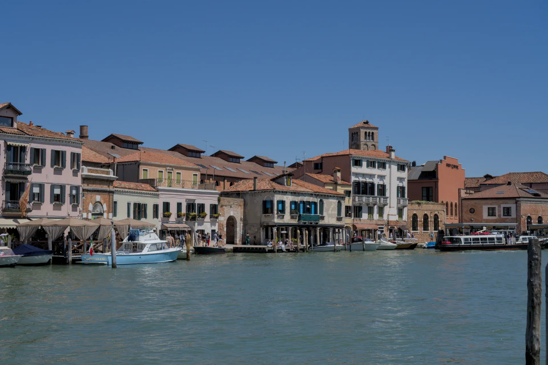 L'architecture distinctive de l'île de Murano à Venise avec des bateaux sur le canal sous un ciel bleu clair.
