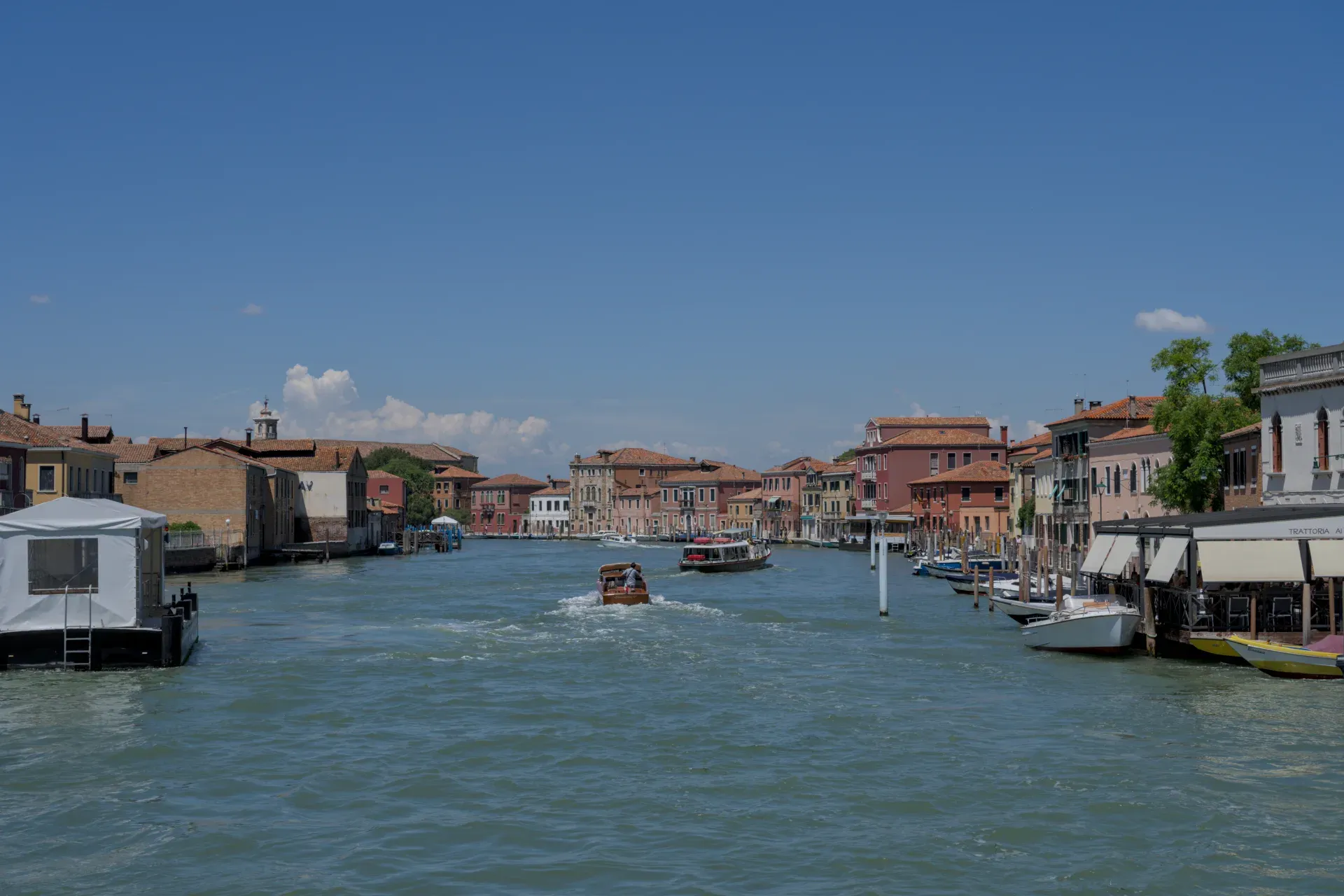 Vista di un canale a Murano, Italia, con edifici colorati e barche sull'acqua.