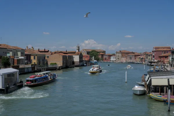 Vue d'un canal sur l'île de Murano à Venise avec des bateaux et des bâtiments traditionnels.