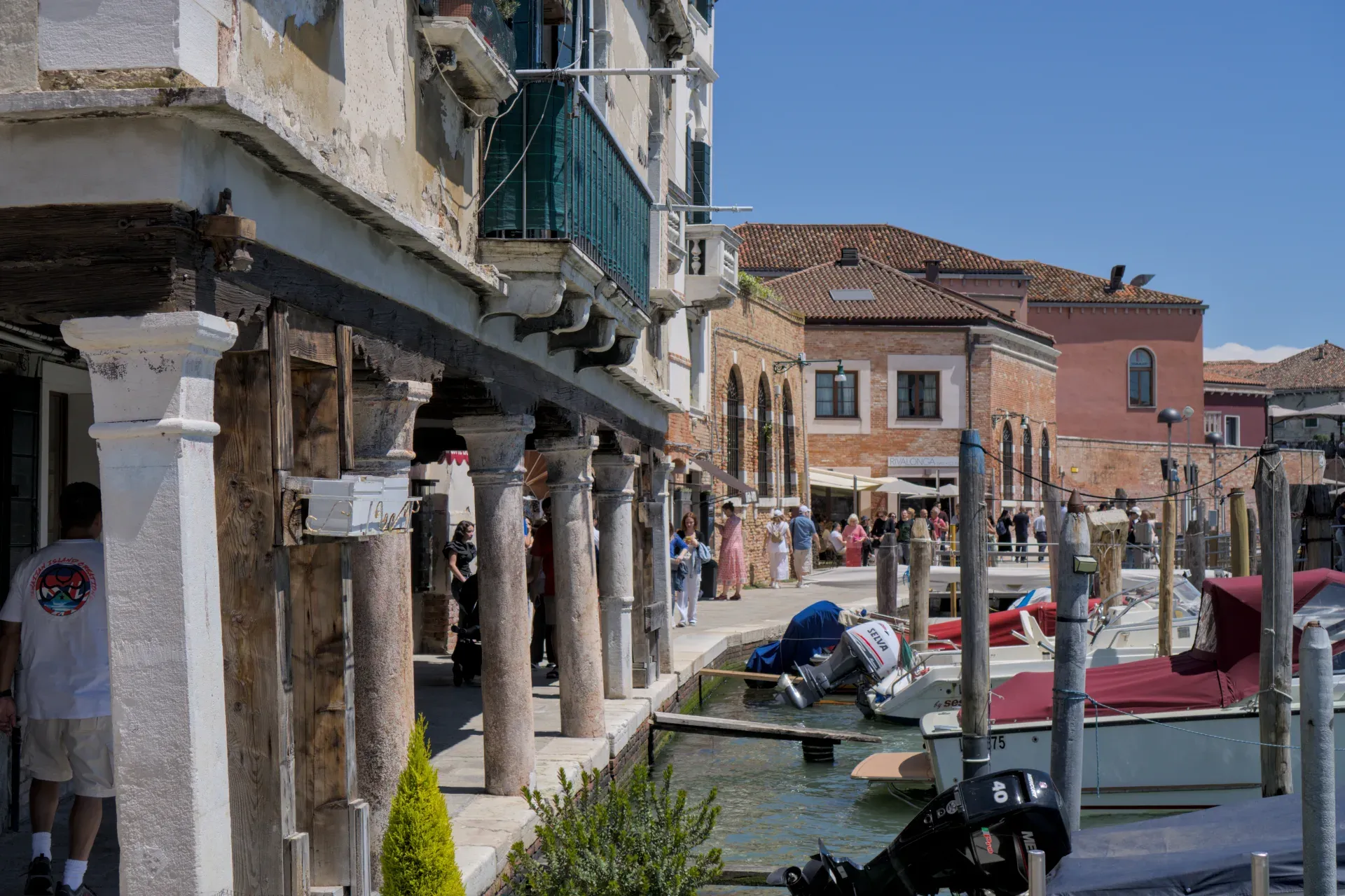 Blick auf den Kai der Insel Murano in Venedig mit Booten und traditionellen Gebäuden.