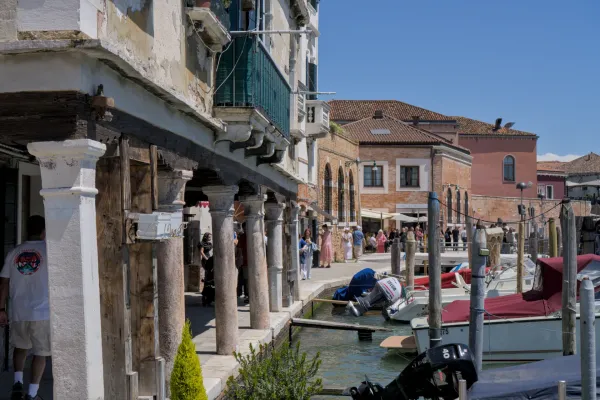 Blick auf den Kai der Insel Murano in Venedig mit Booten und traditionellen Gebäuden.