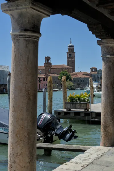 Vue à travers d'anciennes colonnes de l'île de Murano à Venise avec de l'eau turquoise et des clochers.