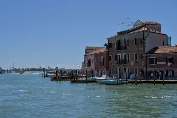 Farbenfrohe Gebäude am Kanalufer von Murano, Italien, mit Booten am Kai.