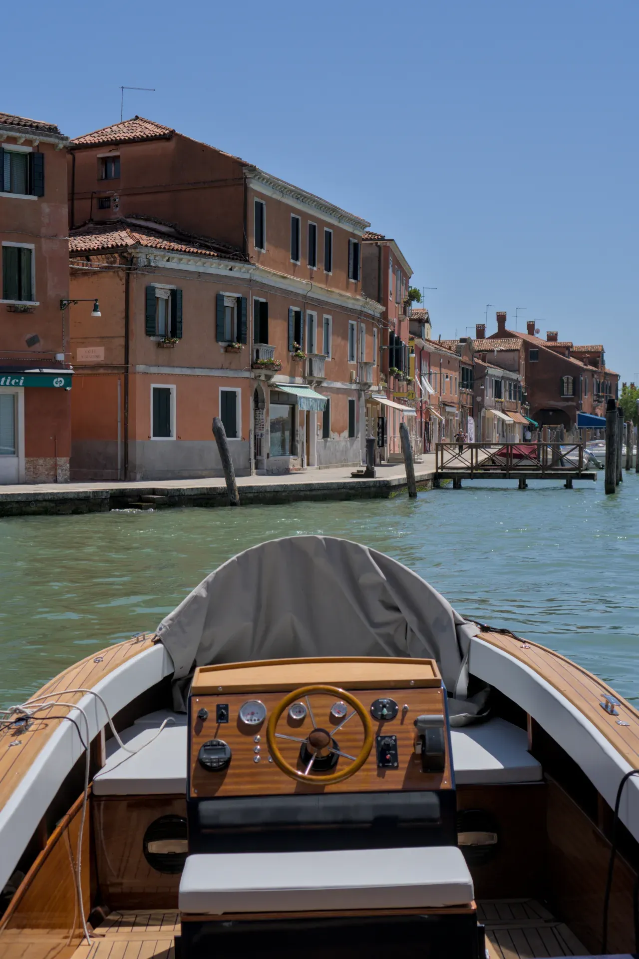 Vue depuis le bateau sur les canaux de Murano, Venise, avec des bâtiments traditionnels et un ciel clair.