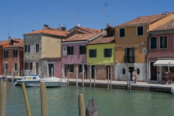 Colorful houses on the canal of Murano island, Venice, with a boat docked.