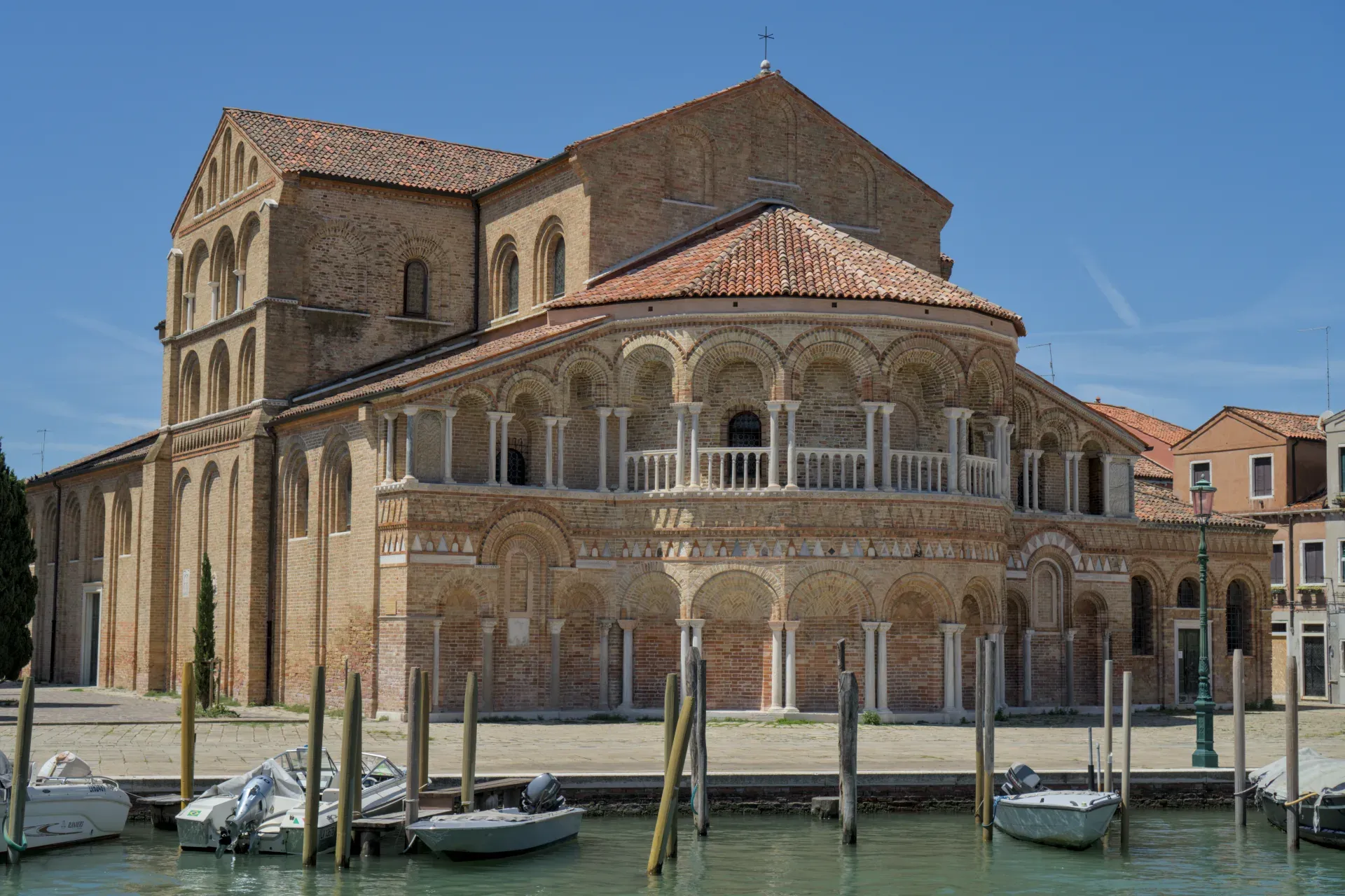 Die Basilika San Donato auf "остров мурано" mit arkadischem Fries und Booten im Wasser.