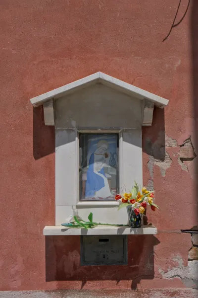 Madonnenbild und Blumen vor einer rötlichen Wand auf der Insel Murano.