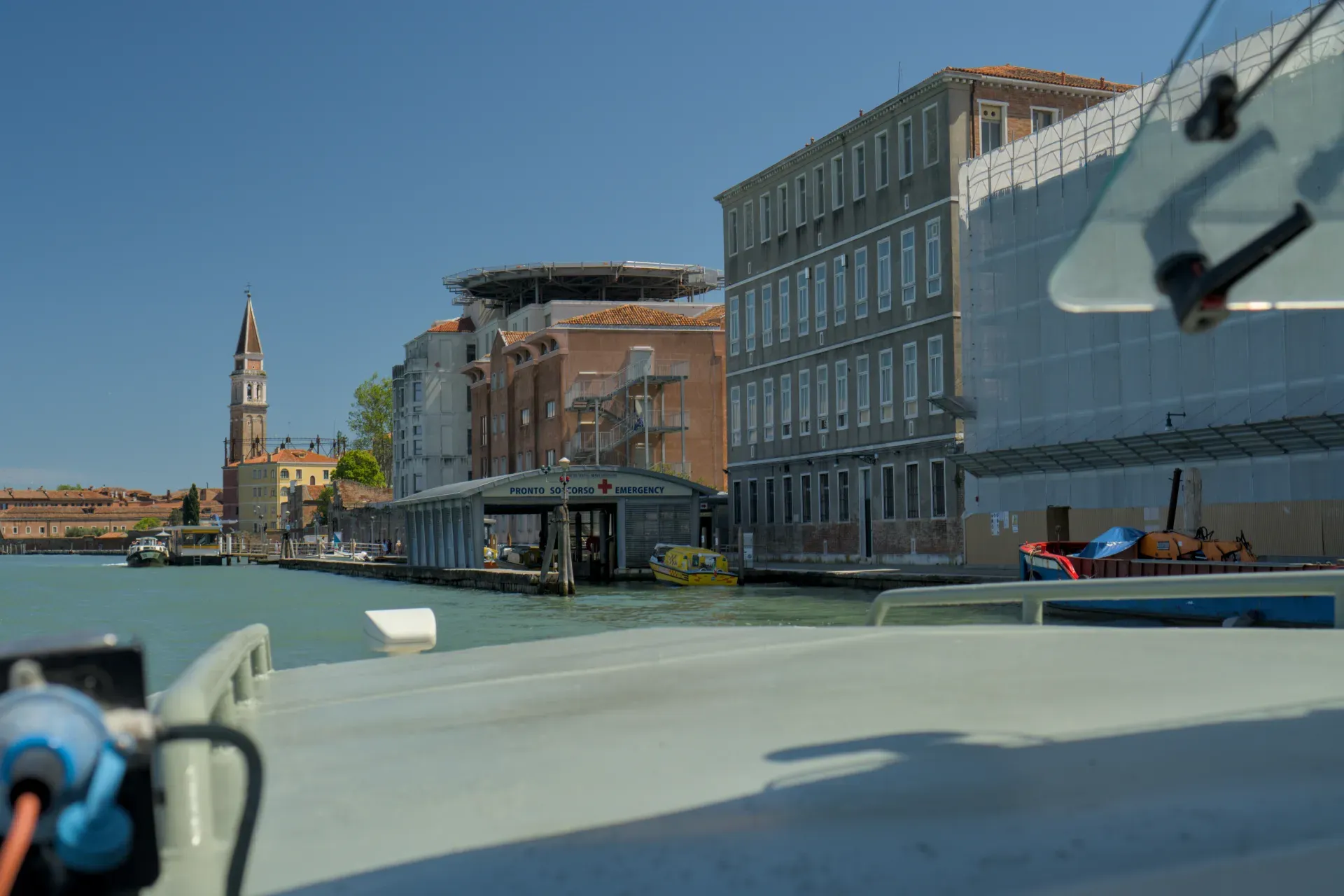 Vue du canal de Venise avec urgences, héliport et campanile sur fond de ciel bleu.