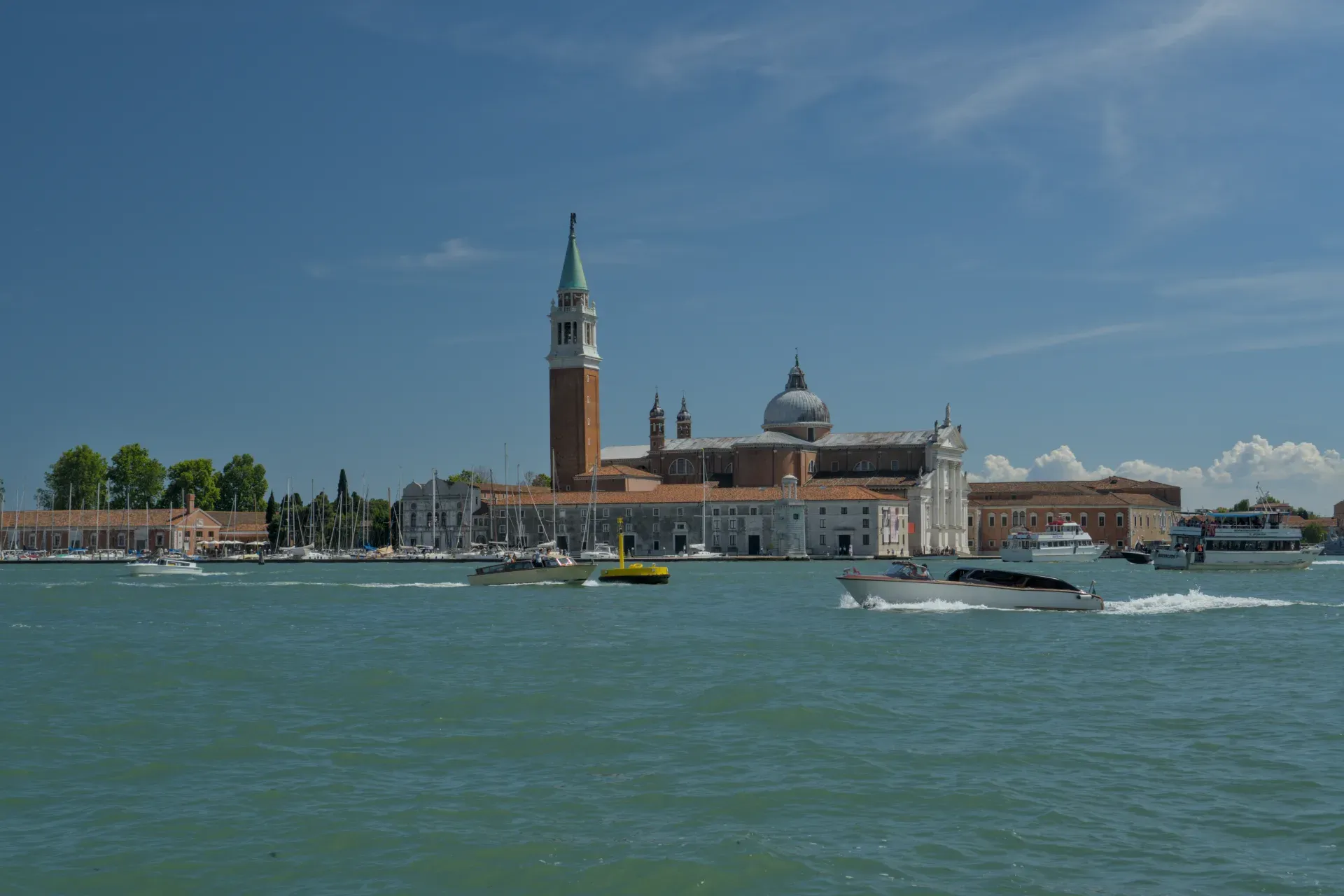 La chiesa di San Giorgio Maggiore a Venezia, Italia, con barche sul Canal Grande sotto un cielo blu.