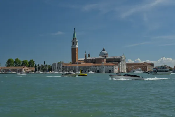 Die Kirche San Giorgio Maggiore in Venedig, Italien, mit Booten auf dem Canal Grande unter einem blauen Himmel.