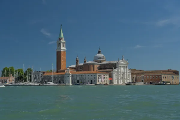 La Basilica di San Giorgio Maggiore con il suo campanile a Venezia, Italia, di fronte a un cielo azzurro limpido e acque calme.