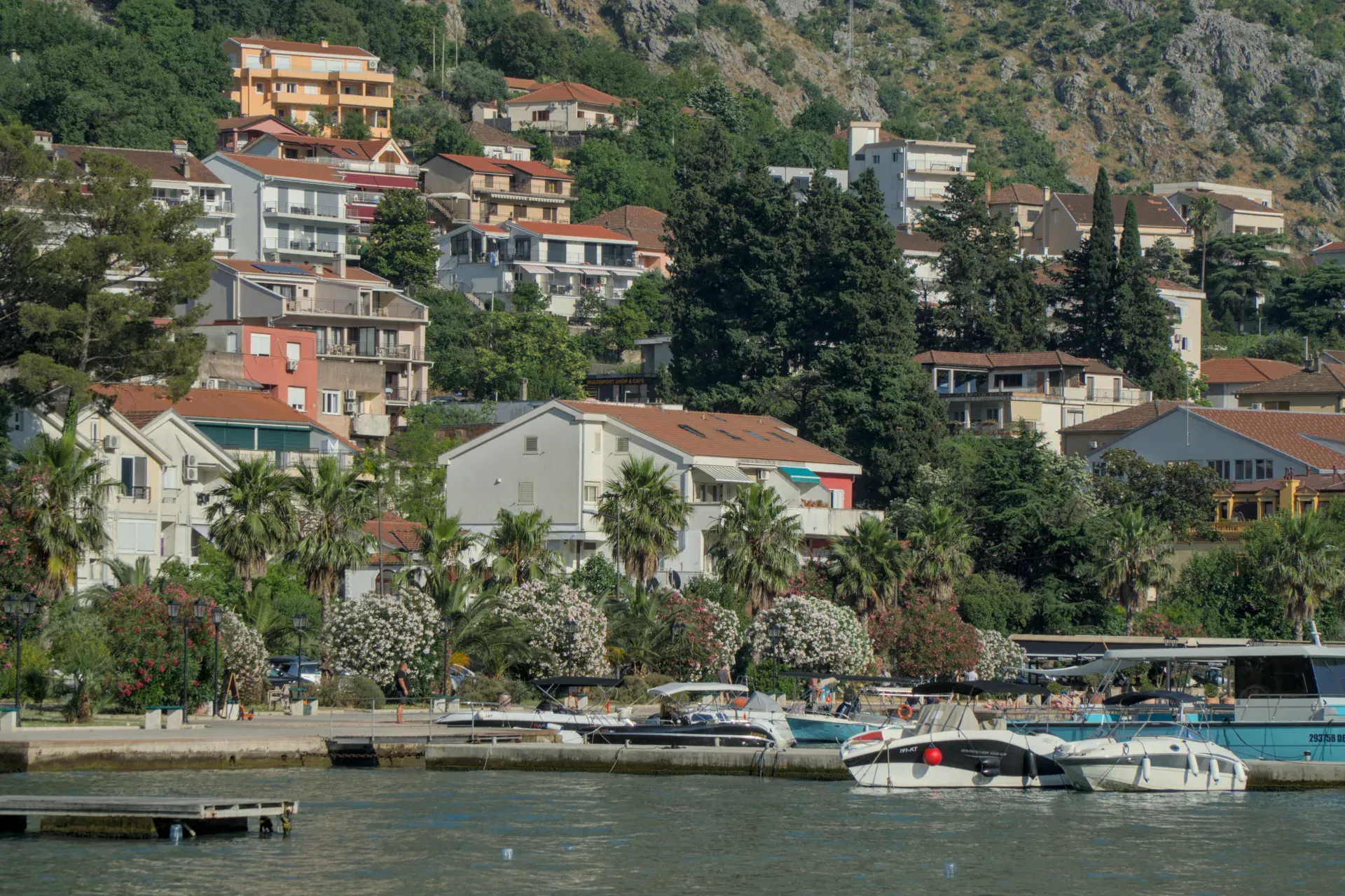 Fotografia di paesaggio della costa di Kotor, Montenegro, con case su una collina e barche sull'acqua.