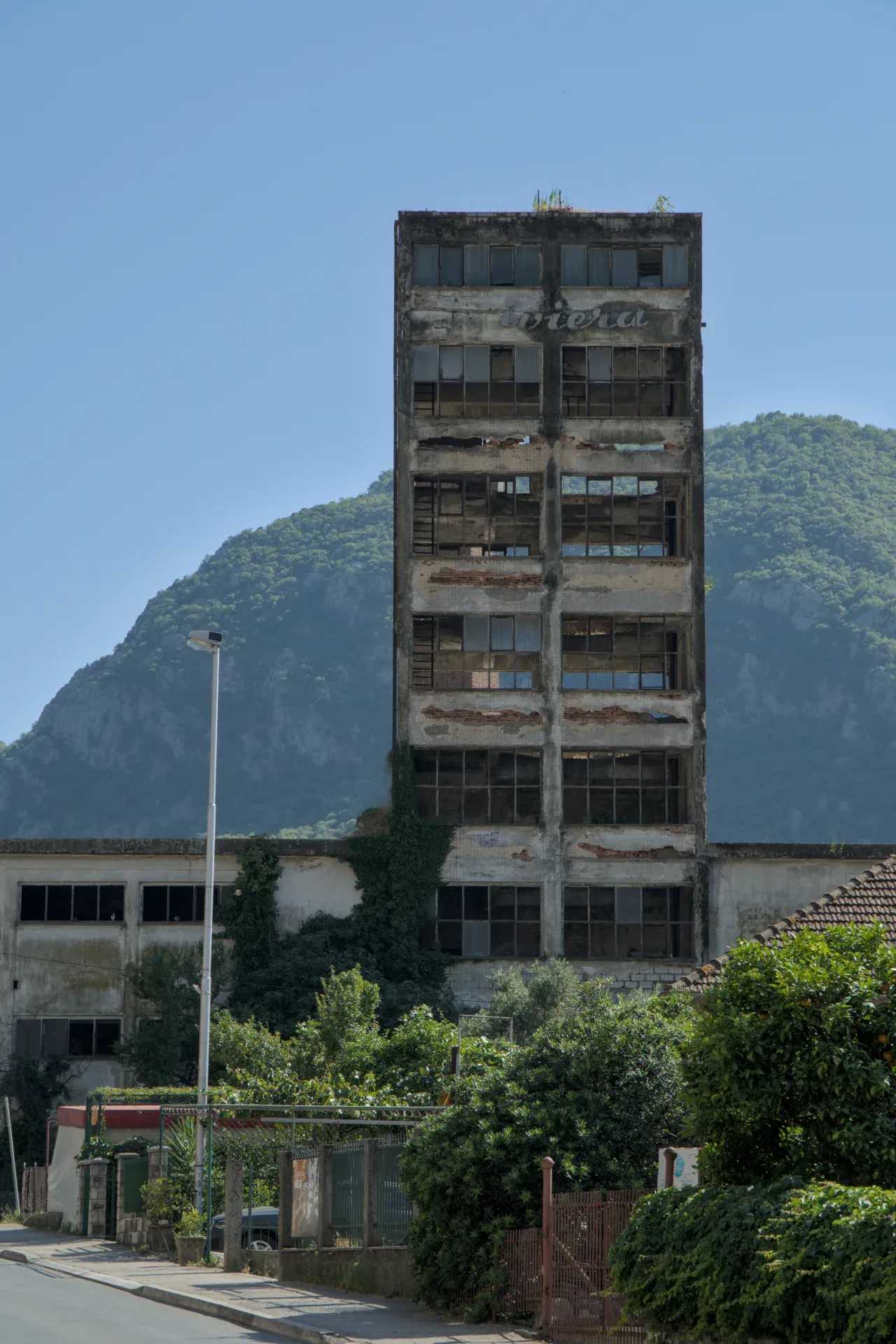 Un bâtiment délabré de plusieurs étages à Kotor, Monténégro, avec des fenêtres et un paysage montagneux en arrière-plan.