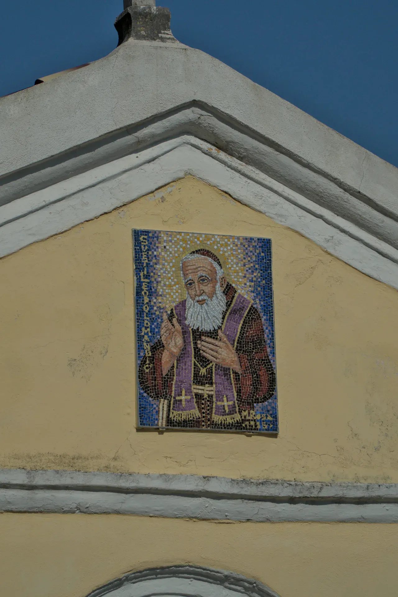 Mosaïque détaillée d'un saint barbu vêtu de pourpre sur une façade jaune à Herceg Novi, Monténégro.