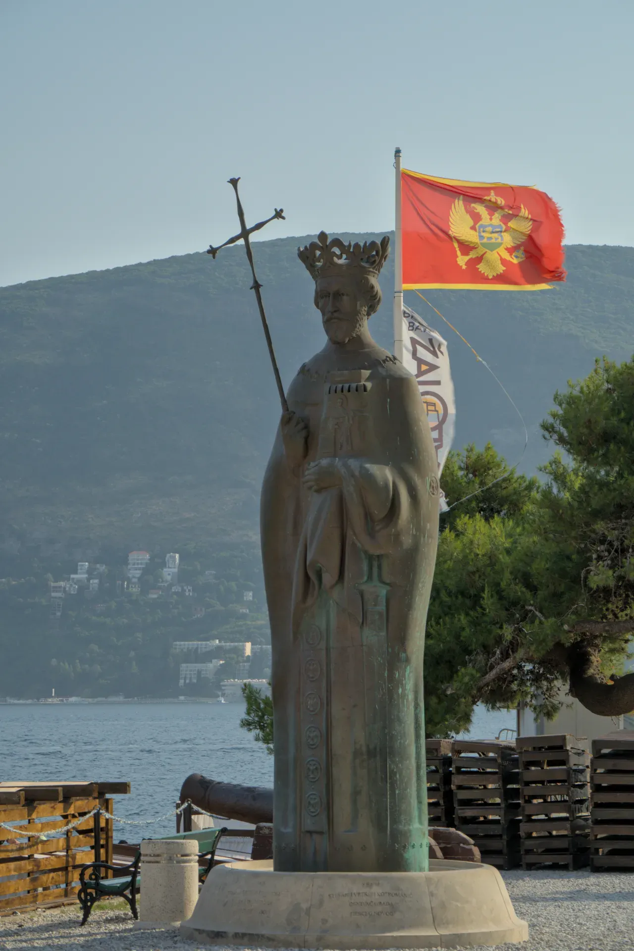Портрет памятника королю в Херцег-Нови, Черногория, с государственным гербом и морем на заднем плане.