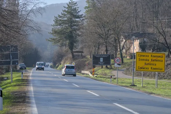 Die Straße von Sremska Kamenica zum Iriški Venac in der Fruška Gora, Serbien, mit Bäumen und vorbeifahrenden Autos.