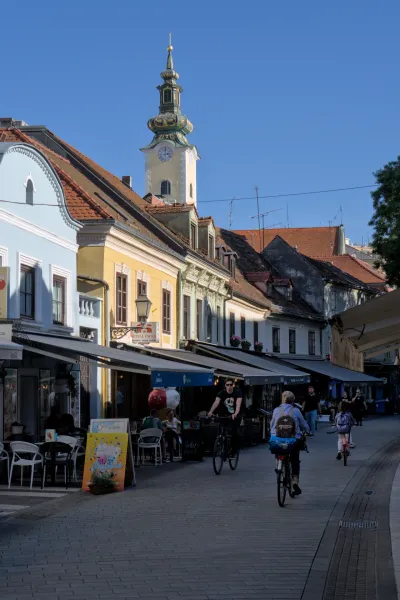 Šarmantna slika uličice u Zagrebu sa istaknutim crkvenim tornjem koji blista na suncu.
