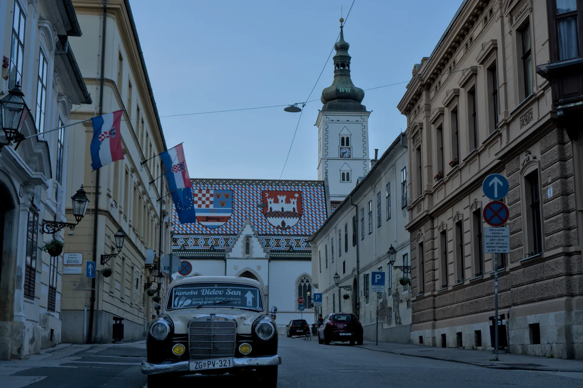 Voiture classique et église Saint-Marc à Zagreb avec des drapeaux croates au crépuscule.